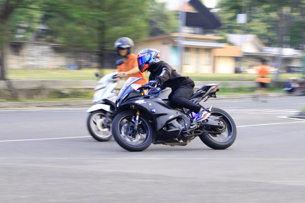 印度尼西亚2024年，骑摩托车的人在城市道路上骑摩托车，背景模糊图片下载