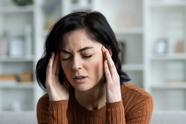 一个年轻女子在家里遭受严重的头痛和偏头痛的特写照片。他双手抱头，按摩，感受到强烈的紧张和压力图片下载