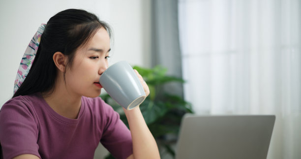 商务女性在家里喝咖啡，用笔记本电脑。图片下载