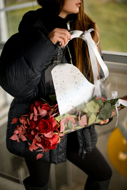 漂亮的年轻女子拿着透明的礼品袋，上面覆盖着闪闪发光的红色玫瑰图片下载