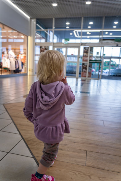蹒跚学步的小女孩穿着紫色卫衣走进商场图片下载