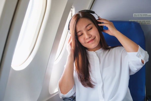 图为一名女子在飞机旅行时戴着耳机听音乐图片下载
