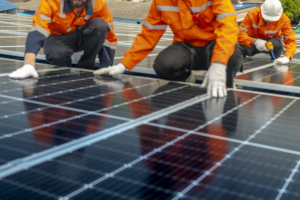 两名工程师检查新安装的黑色太阳能电池板，穿着反光背心的技术人员的倒影模糊。包括带有模糊线路的太阳能电池板的图片。图片下载