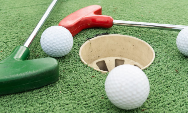 迷你高尔夫。高尔夫球场上的一根球杆和一个白球。图片下载