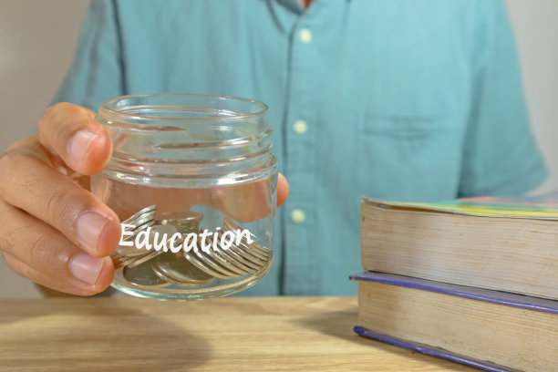 一名男子拿着一个装满教育基金硬币的玻璃罐。为教育省钱的理念。图片下载