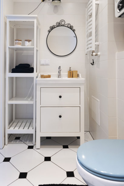 室内陶瓷浴室，白色瓷砖墙面与圆形镜子，温馨的乡村风格。竖版照片图片下载