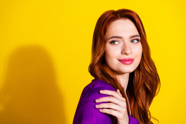 肖像照片的红头发华丽的女人在紫色缎面衬衫触肩显示她的化妆孤立的黄色背景图片下载