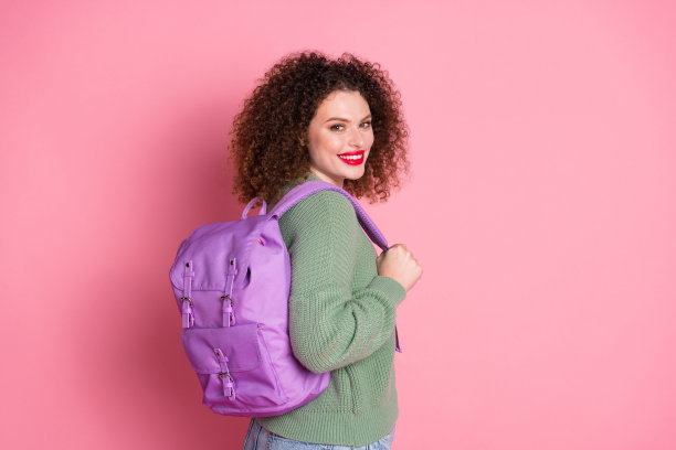 照片中开朗的漂亮可爱的女人穿着时髦的卡其色衣服，拿着粉红色背景上孤立的包图片下载