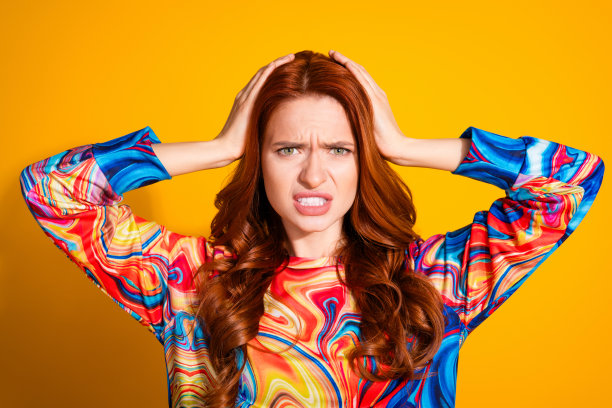 照片上的年轻美女摸着头吓得紧张，穿着时髦的彩色衣服，孤立在橙色的背景上图片下载