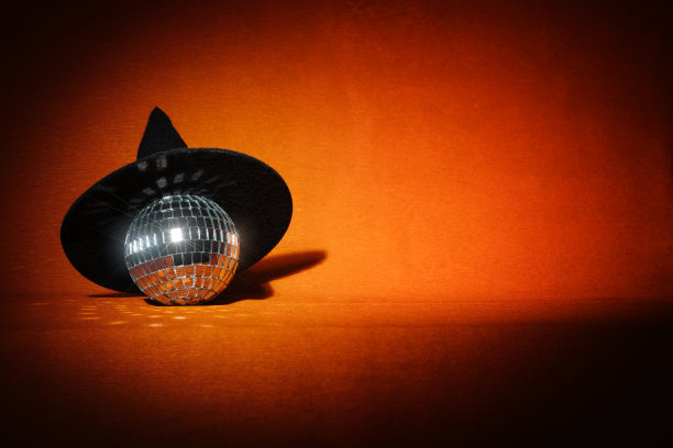 橙色万圣节背景上的女巫帽和迪斯科球图片下载