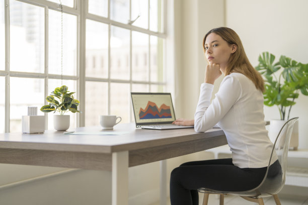 一名女子在城市阁楼里一扇明亮的大窗户旁工作图片下载