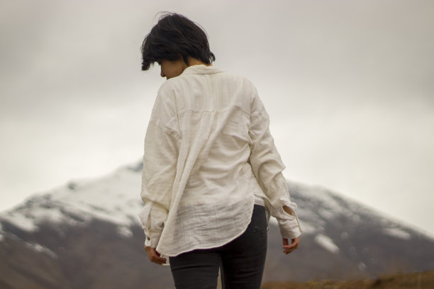 穿着白衬衫的短发年轻女士的肢体语言照片，背景是雪山风景图片下载