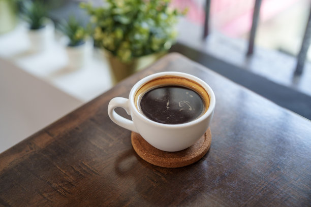 窗边木桌上一杯黑咖啡的高角度照片。图片下载
