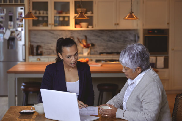 一位高级妇女在家里舒适舒适的厨房里接受财务方面的帮助。图片下载