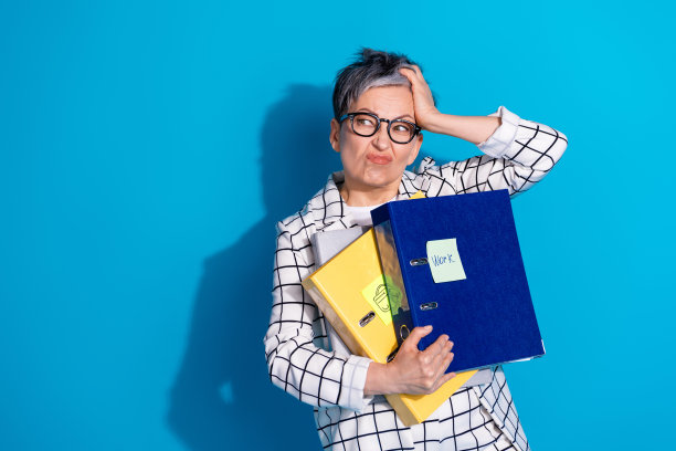 照片中，悲伤沮丧的退休妇女穿着白色西装，摸着头，在蓝色背景上看起来空空荡荡图片下载