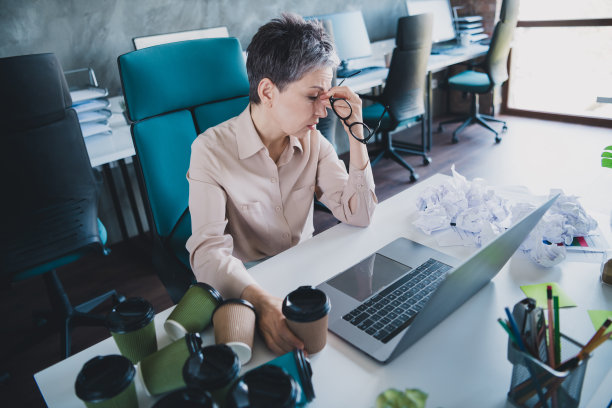 过度劳累的不快乐年龄的女特工的照片穿着正式的衬衫在室内工作的工作站阁楼的现代小工具图片下载