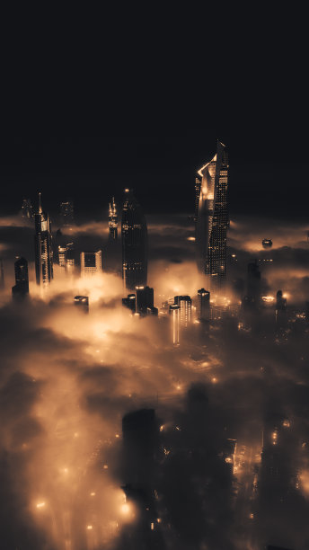 科威特城摩天大楼在雾蒙蒙的夜晚穿透云层的航拍照片图片下载