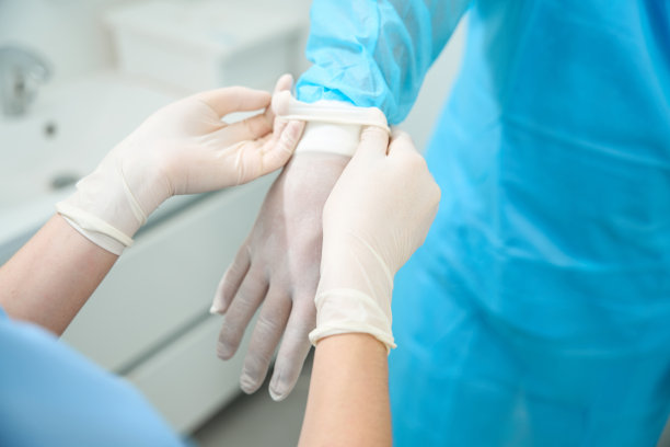 剪短的女护士帮助男医生戴上乳胶手套的图片图片下载