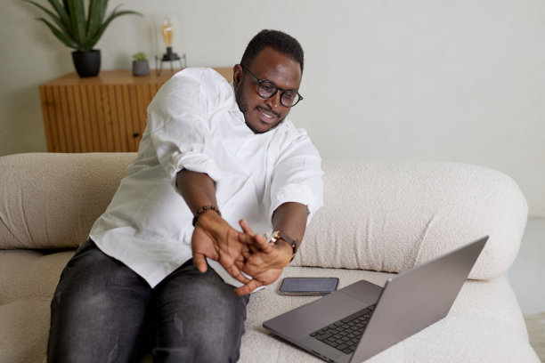 在舒适的家中用笔记本电脑工作了很长时间后，年轻的商人伸出双手图片下载