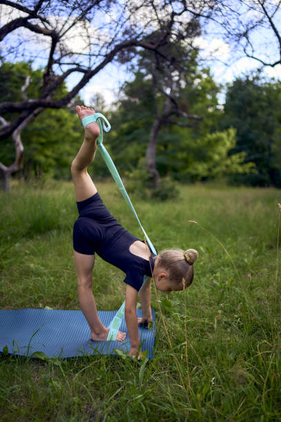 5岁的小女孩穿着黑色的极简主义服装，在室外的花园里做体操图片下载