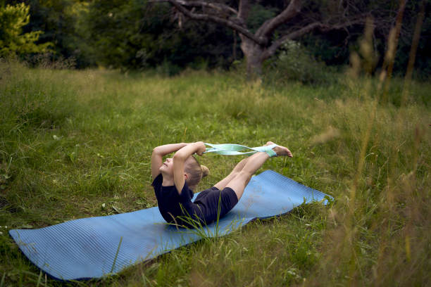 一个5岁的小女孩穿着黑色的极简主义连衣裤在室外的花园里做体操图片下载