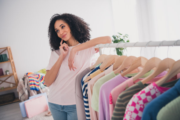 照片中可爱迷人的漂亮女孩穿着时髦的衣服，在室内选择装备衣柜图片下载