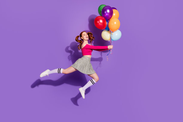 全身照片迷人的积极的女孩穿粉红色的顶跳抱气球束空空间孤立的紫色背景图片下载