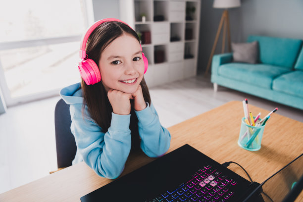 可爱可爱的女孩坐在家里的桌子上学习现代科技设备的照片图片下载