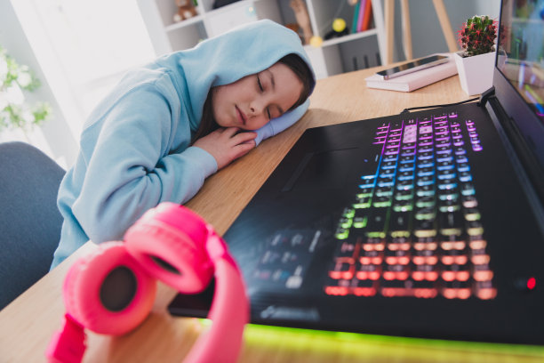 照片中可爱可爱的疲惫女孩在室内玩完游戏木桌后睡着了图片下载