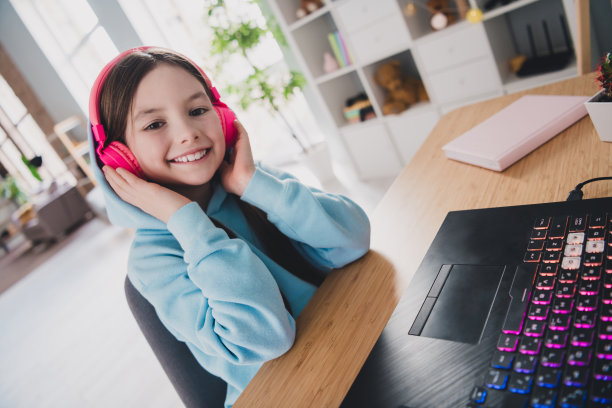 漂亮可爱的女孩的照片小玩家触摸设备使用现代科技电脑在室内的房子图片下载