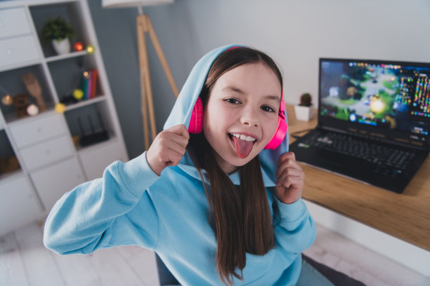 照片开朗快乐时髦可爱的女孩小玩家周末空闲时间在线视频电脑游戏室内的房子图片下载