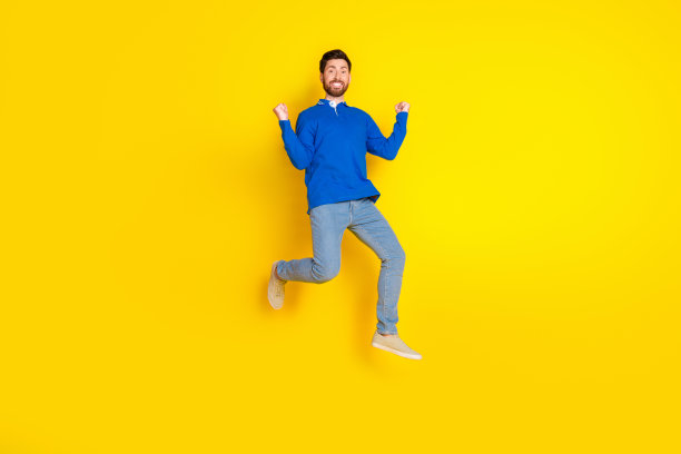 英俊的年轻人赢得跑步的全身照片穿着时尚的蓝色服装孤立的黄色背景图片下载