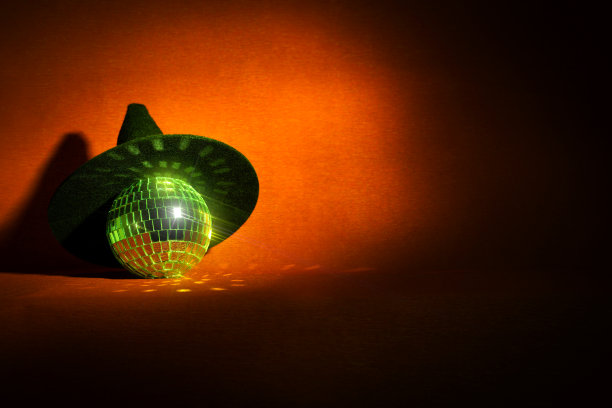 橙色万圣节背景上的女巫帽和迪斯科球图片下载