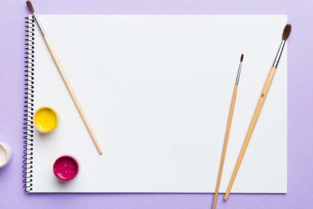 相册页和油漆，铅笔，画笔在彩色的背景。空白处的俯视图。创造的工作场所。家庭教学概念图图片下载