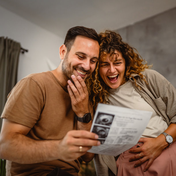 丈夫抱着妻子看孩子的超声波照片图片下载