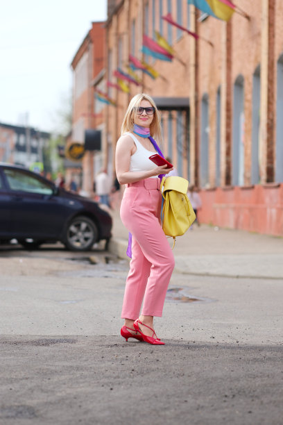 戴丝巾的女士在过马路时从皮包里取下钱包图片下载