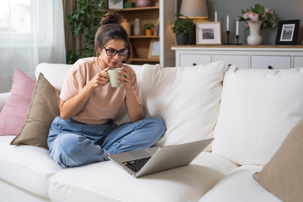 年轻女性在线约会或在家视频聊天，与男友或朋友在笔记本电脑上喝咖啡或茶。女性在舒适的公寓里使用科技产品，放松身心。图片下载