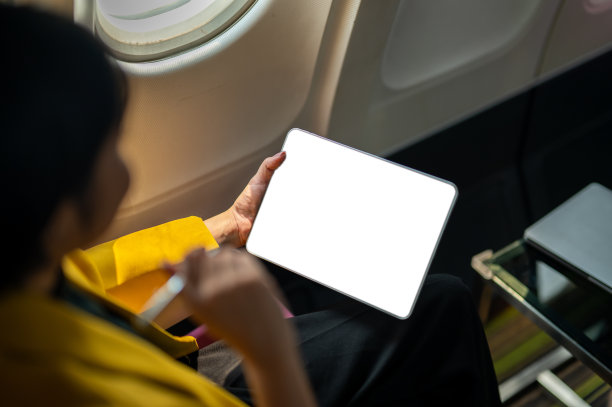 一位女商人在飞机上使用笔记本电脑的俯拍照片，捕捉了现代旅行和工作灵活性的精髓。图片下载