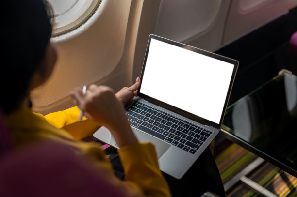 一位女商人在飞机上使用笔记本电脑的俯拍照片，捕捉了现代旅行和工作灵活性的精髓。图片下载
