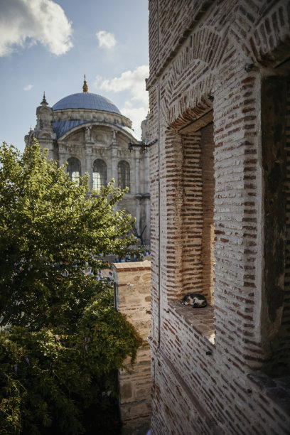 一只可爱的猫蜷缩在窗户边休息，窗外可以看到Ortaköy清真寺。库存图片图片下载