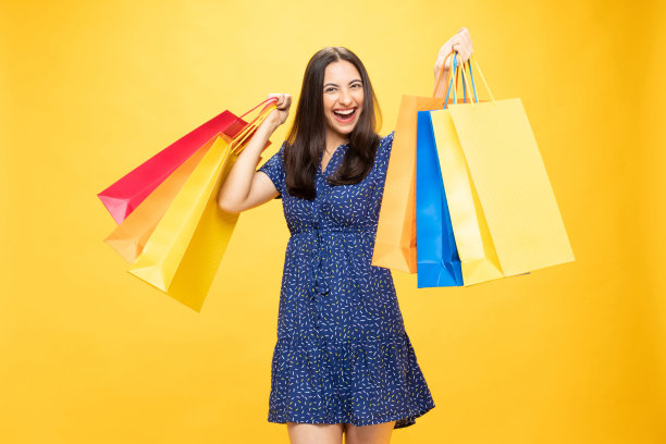 购物的照片欢快的女孩手里拿着彩色的袋子孤立在明亮生动的亮黄色背景股票照片图片下载