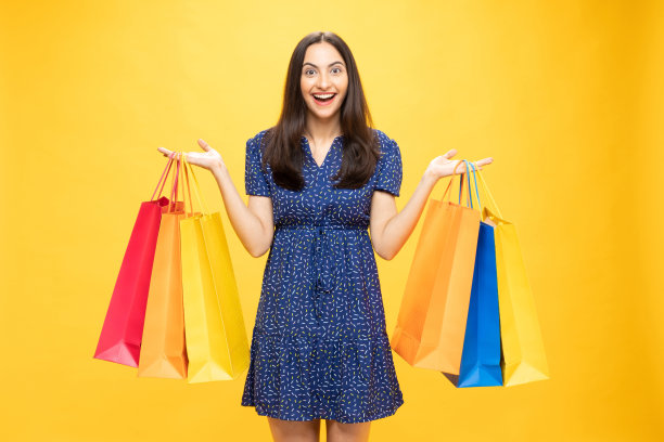 购物的照片欢快的女孩手里拿着彩色的袋子孤立在明亮生动的亮黄色背景股票照片图片下载