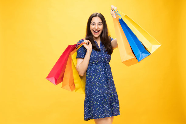购物的照片欢快的女孩手里拿着彩色的袋子孤立在明亮生动的亮黄色背景股票照片图片下载