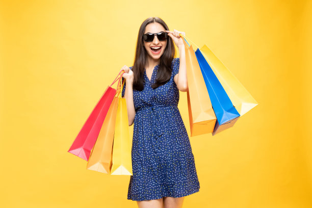 购物的照片欢快的女孩手里拿着彩色的袋子孤立在明亮生动的亮黄色背景股票照片图片下载