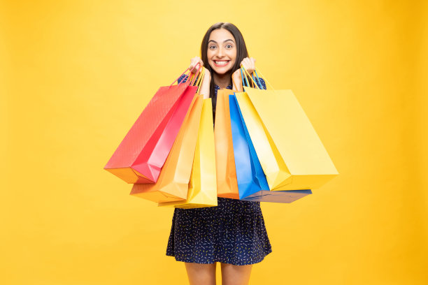 购物的照片欢快的女孩手里拿着彩色的袋子孤立在明亮生动的亮黄色背景股票照片图片下载