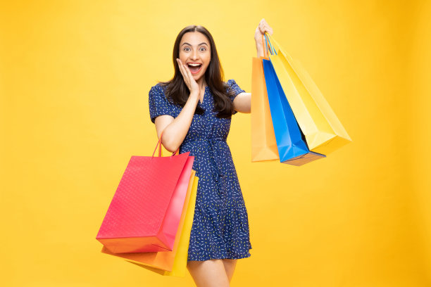 购物的照片欢快的女孩手里拿着彩色的袋子孤立在明亮生动的亮黄色背景股票照片图片下载