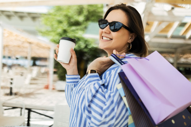 快乐的年轻女子在阳光下拿着包图片下载