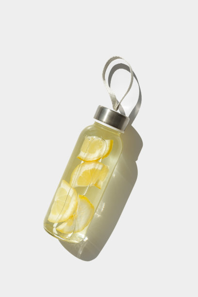 顶视图玻璃瓶，柠檬水喝排毒，阳光阴影，自然光，白色背景，copyspace。用柑橘片浸泡水。极简美学的照片和新鲜的饮料图片下载