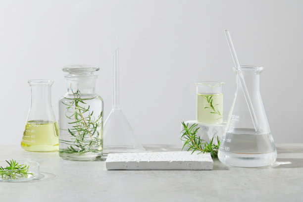 天然提取物产品广告照片，中间为空的展示台座，两侧展示实验室玻璃器皿，内含透明的黄色液体。正面射击，复制空间图片下载