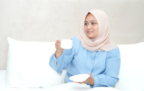 亚洲女人坐在卧室里拿着茶杯图片下载